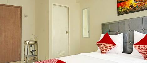 A hotel room with a large bed, a painting on the wall, and a water dispenser.