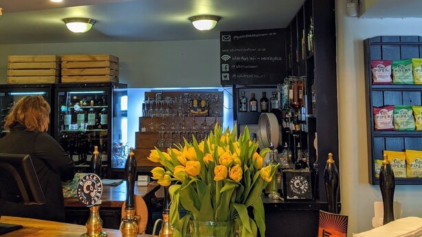 The White Hart Inn's exterior with a sign, a flower arrangement, and a bar area visible inside. - The White Hart Inn (Hawes)
