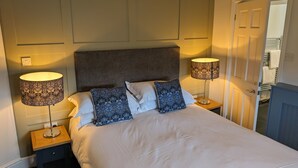 A neatly made bed with a white duvet and two decorative pillows, flanked by two bedside lamps with patterned shades. - The White Hart Inn (Hawes)