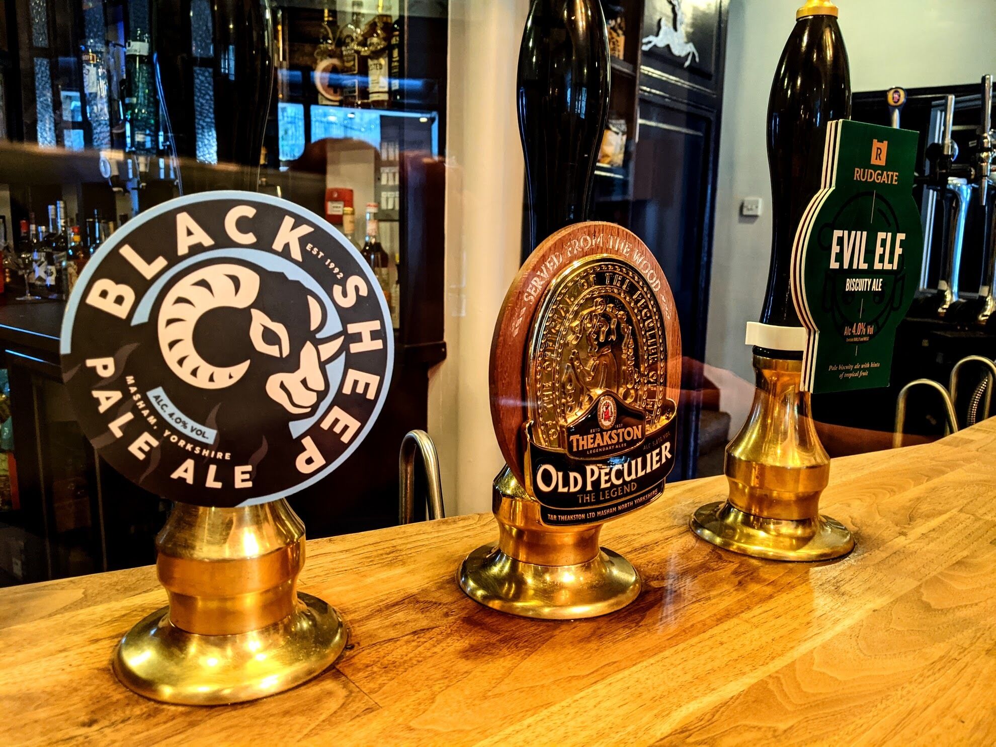 A bar counter with three beer taps: Black Sheep Pale Ale, Old Peculier, and Evil Elf Biscuit Ale.