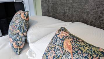 A bed with white linens and two decorative pillows with a floral pattern.