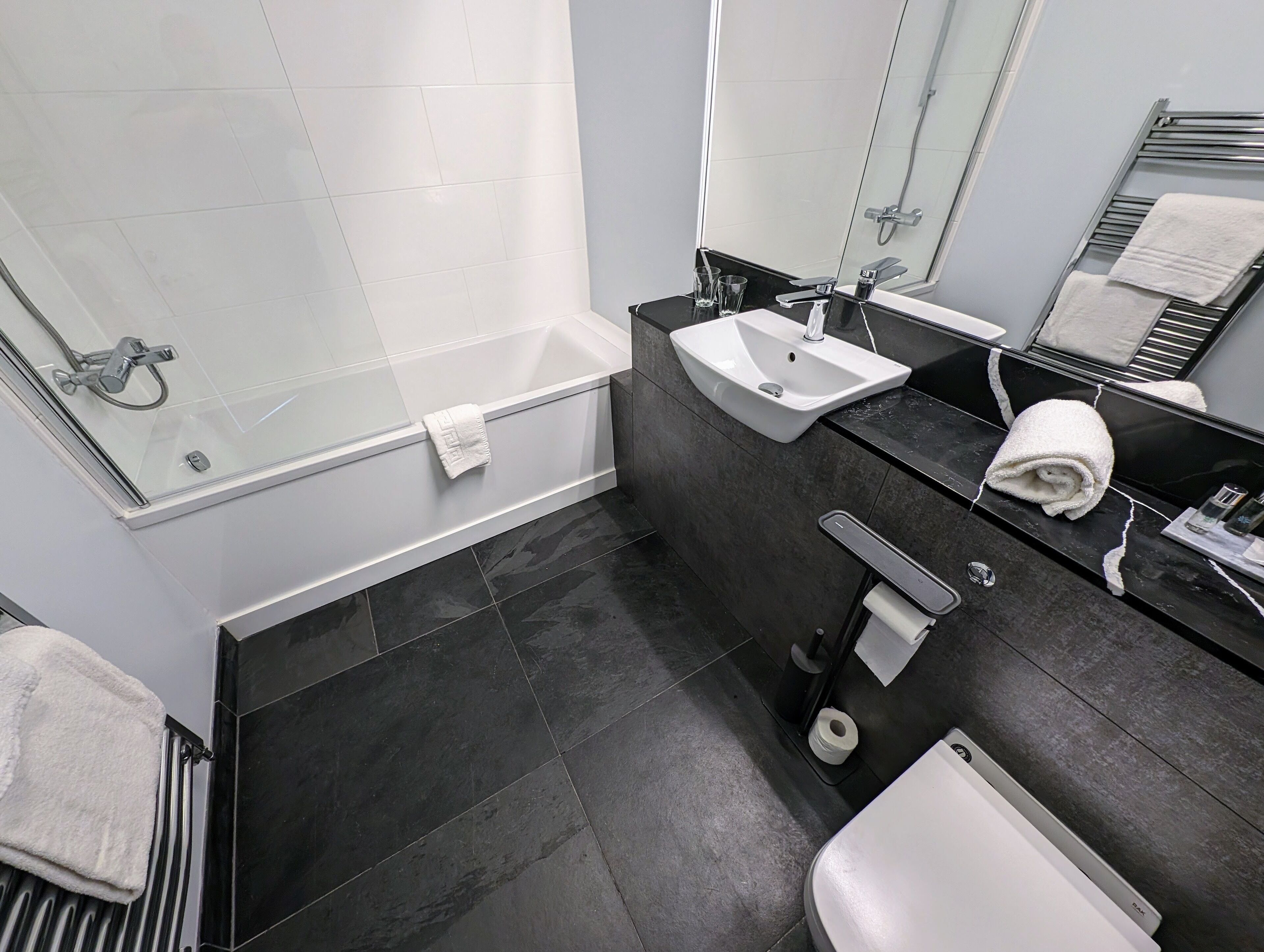 Un baño moderno con bañera, lavamanos, inodoro y cabina de ducha de vidrio.