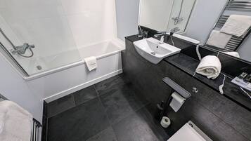 Un baño moderno con bañera, lavamanos, inodoro y cabina de ducha de vidrio.