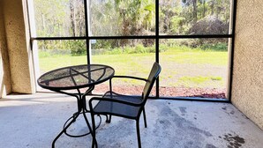 A room with a large window, a round metal table, and a single chair.