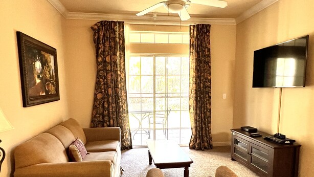 A living room with a sofa, armchair, coffee table, and a TV on a stand.