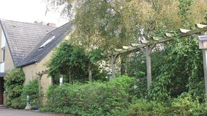 A residential area with a house, a pergola, and dense greenery. - Deichkind * Holiday apartment on the North Sea in Husum * At home by the sea (Husum)