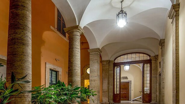A spacious corridor with high ceilings, large columns, and a chandelier. - Stay in the heart of Rome (Roma)
