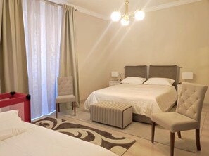 A hotel room with a bed, two bedside tables, a chair, a bench, a red storage unit, and a window with curtains. - Stay in the heart of Rome (Roma)