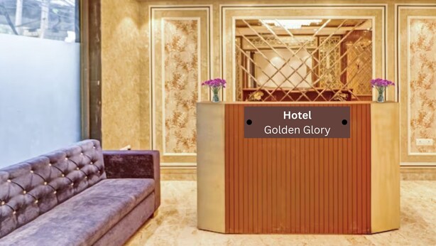 A reception area with a wooden reception desk labeled "Hotel Golden Glory," a tufted sofa, and a large window. - Hotel Golden Glory (New Delhi)