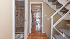 A hallway with a wooden floor, a stone wall, and a white staircase. - Beautiful townhouse with outdoor pool  Free WiFi, linens included and right at the beach. (Ocean City)