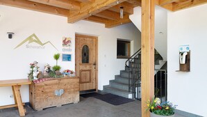 A reception desk with a wooden counter, a door with glass panels, a staircase, and a wall-mounted light fixture.