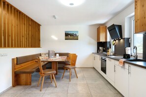 Eine moderne Küche mit Holzausstattung, einem Essbereich mit einer Bank und einem großen Fenster.