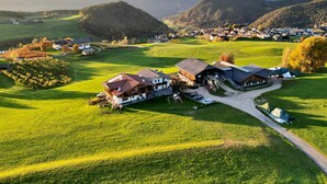 A rural village with traditional buildings, a green field, and a mountain backdrop.