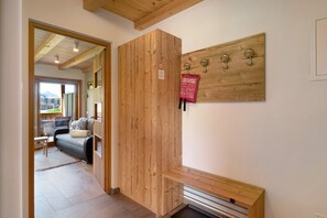 Un intérieur en bois avec un canapé, un banc et un porte-manteau fixé au mur.