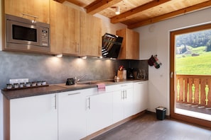 Une cuisine moderne avec des meubles en bois, un four à micro-ondes en acier inoxydable et un four encastré.