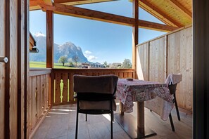 A wooden cabin with a table and chairs, a view of mountains, and a wooden railing. - Apartment 'Schererhof Morgenrot' with Mountain View, Private Terrace and Wi-Fi (Castelrotto)