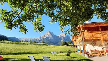 A wooden chalet with a mountain view, outdoor seating, and a garden.