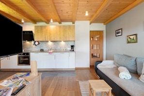 Een moderne keuken met houten kastjes, een inbouwoven en een eethoek met een tafel en stoelen.