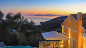 A poolside area with a view of the sea and mountains at sunset. - Villa Kalamia in Kalami (Corfu)