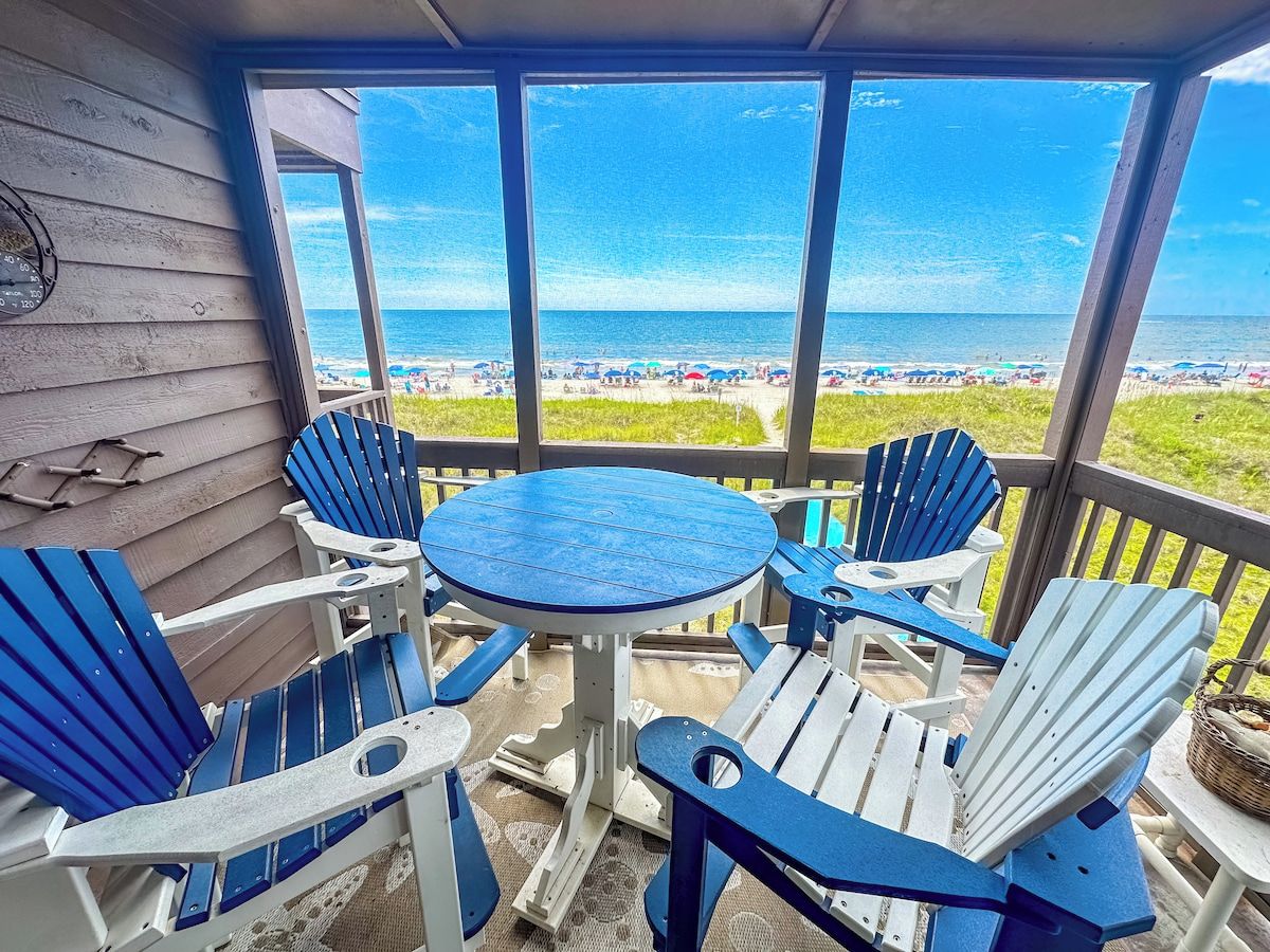 A covered outdoor seating area with a view of the beach.