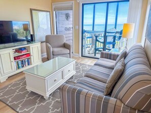 A living room with a sofa, a coffee table, a television, and a bookshelf. - Tilghman Beach and Racquet Club 221 (North Myrtle Beach)