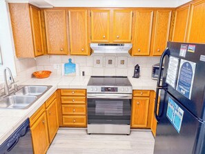 A kitchen with wooden cabinets, stainless steel appliances, and a black refrigerator.