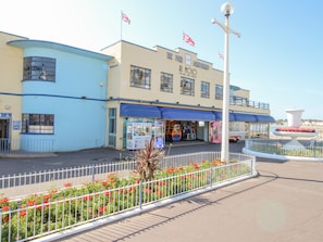 A seaside building with a restaurant named "The Pier" and "Al Molo" signs, a small kiosk, and a fountain. - Pam's House (Weymouth)