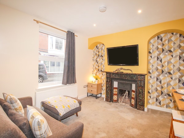 A living room with a sofa, a fireplace, a television, and a patterned wall. - Pam's House (Weymouth)