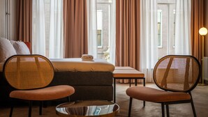 A hotel room with a bed, two wicker chairs, a small table, and a floor lamp. - Hotel Halbert (Groningen)