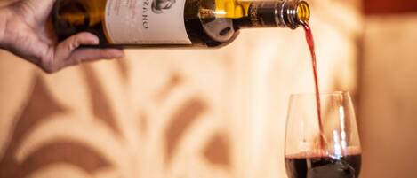 A hand pouring wine from a bottle into a glass.