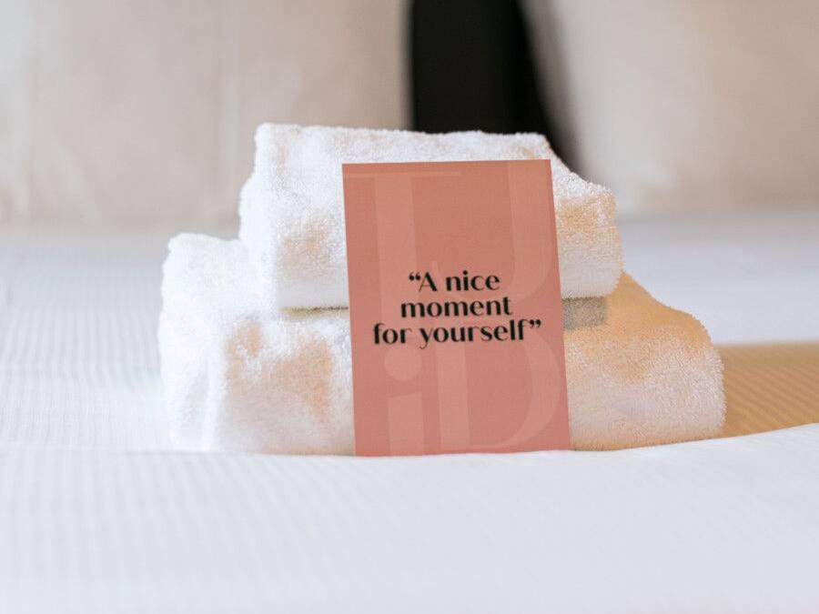 Una cama bien hecha con sábanas blancas y una etiqueta que dice 'Un momento agradable para ti'.