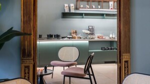 A room with a large ornate mirror, two chairs, a small table, and a kitchen area visible through the mirror. - Hotel Halbert (Groningen)