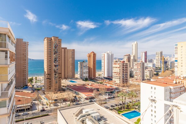 A high-rise building with a pool, surrounded by other buildings and a clear sky.