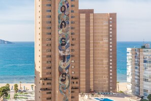 A high-rise building with a distinctive mosaic design on its facade, overlooking a beach and the sea.
