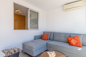 A modern living room with a grey sofa, a small round table, and a window with a view.