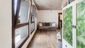 Une pièce avec un plancher en bois, un canapé, une table et un meuble orné d’un motif de feuilles vertes.
