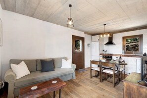 Un espacio habitable compacto con sofá, mesa de comedor y kitchenette.