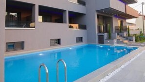 A modern building with a swimming pool, multiple balconies, and a flat roof design. - Yakinthos Hotel (Katerini)