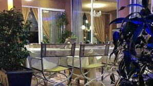 An outdoor seating area with metal chairs and tables, surrounded by potted plants. - Yakinthos Hotel (Katerini)
