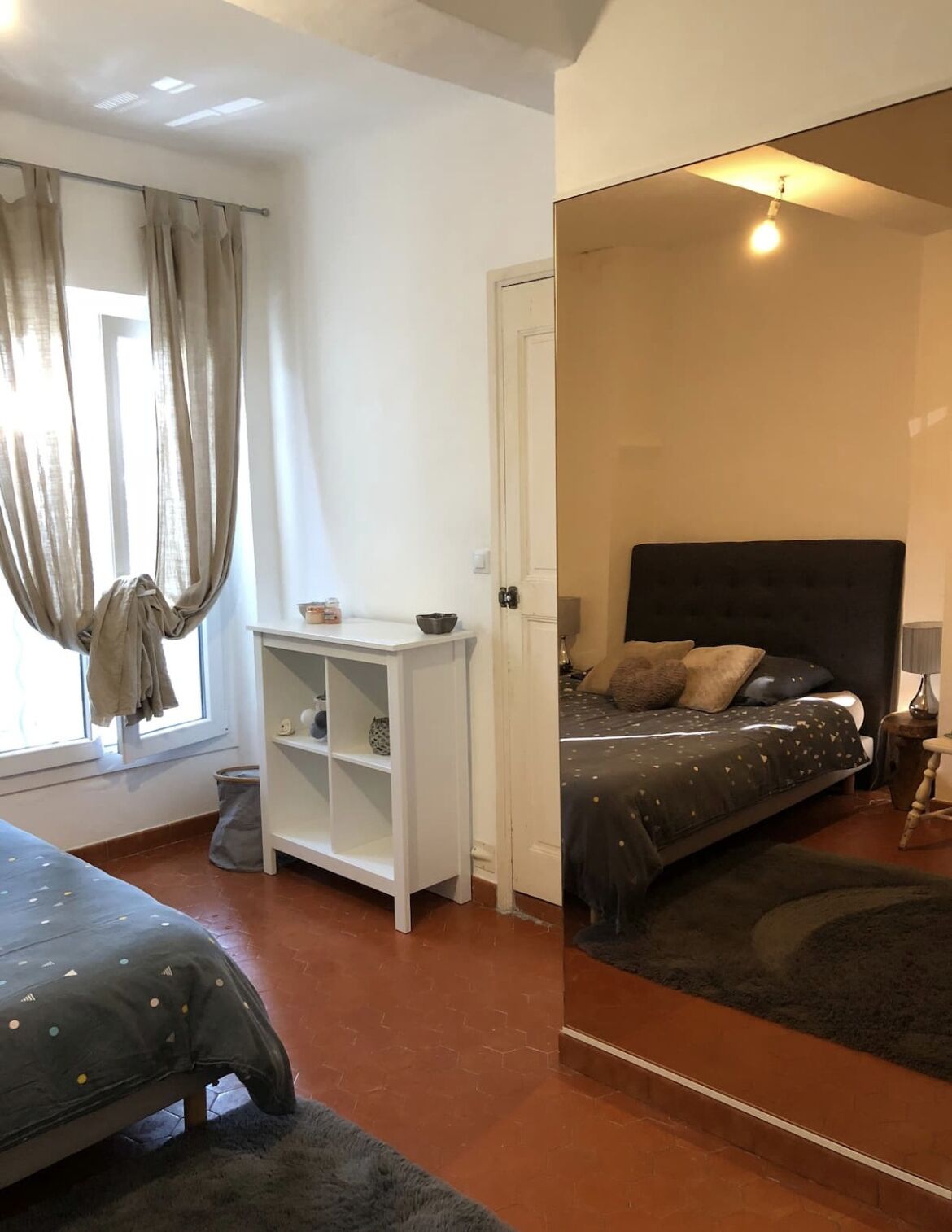 A bedroom with a bed, a desk, a chair, and a window with curtains.