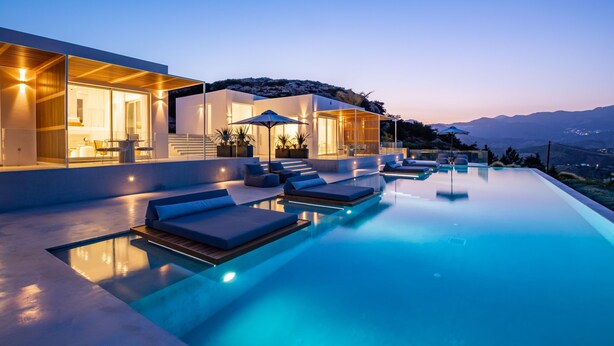 A modern infinity pool with lounge chairs and a glass-enclosed patio area. - Istia Luxury Villas (Karpathos)