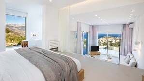 A modern bedroom with a large bed, a view of the sea, and a balcony. - Istia Luxury Villas (Karpathos)