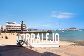 A beachside view with a sign reading 'CORRALEJO' and a building in the background.