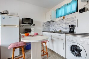 A compact kitchen with a microwave, toaster, sink, and washing machine.