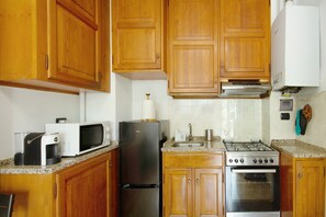 A kitchen with wooden cabinets, a microwave, a refrigerator, a stove, and a sink.