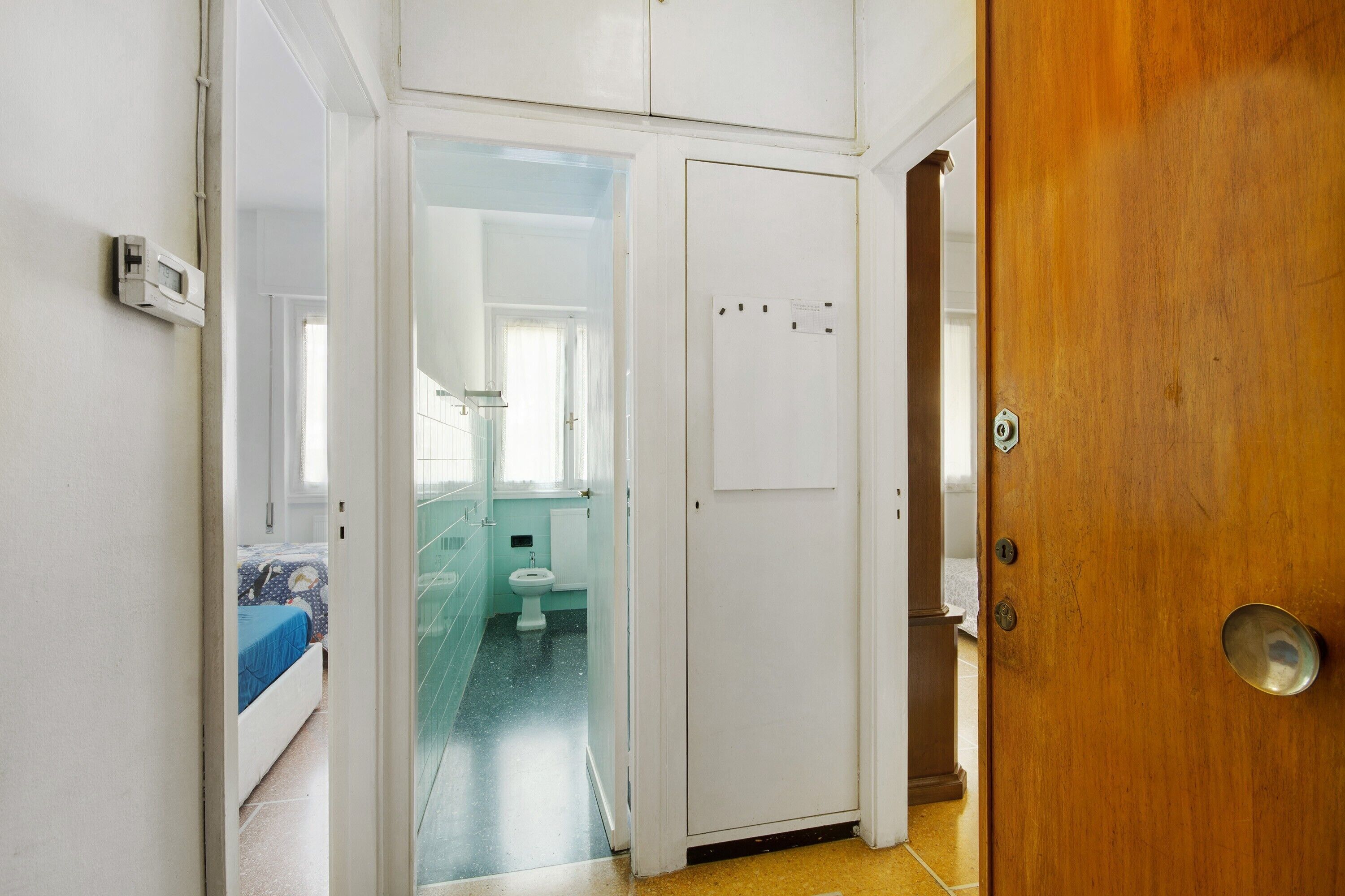 Una habitación con cama, baño con inodoro y lavamanos, y una puerta de madera.
