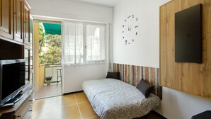 Ein Schlafzimmer mit Bett, Fernseher, Fenster und einer Uhr an der Wand.