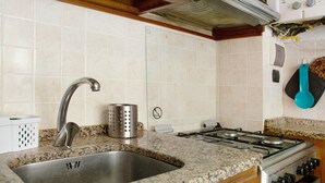 Eine Küche mit Spüle aus Edelstahl, einer Arbeitsplatte aus Granit und einem Gasherd.