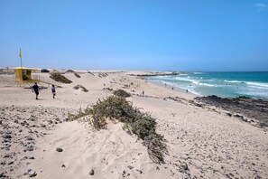 Une plage avec une tour de surveillance pour les sauveteurs, des dunes de sable et l’océan.