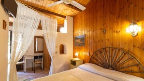 A bedroom with a wooden ceiling, a bed with a metal headboard, a desk with a chair, and a nightstand with a lamp. - Holiday Home 'Fattoria Spezia - Nespola' with Shared Pool, Garden and Shared Wi-Fi (Buseto Palizzolo)